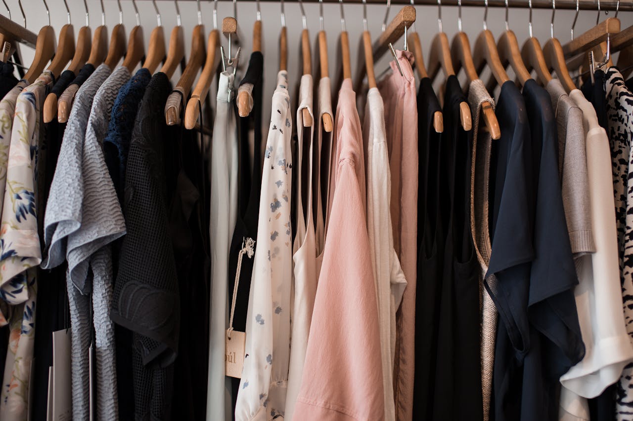 A stylish collection of womens clothing hanging on wooden hangers in a boutique setting.